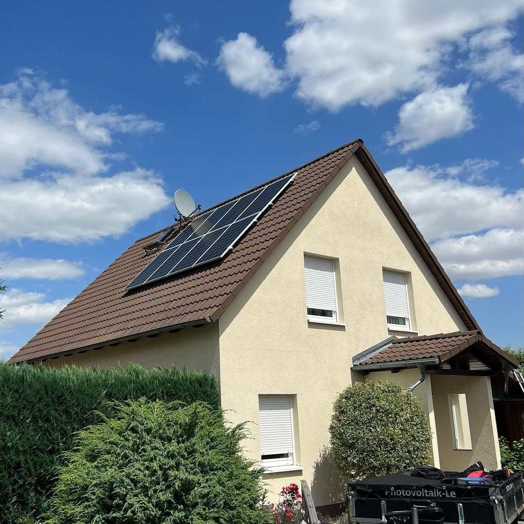 Gelbes Einfamilienhaus mit braunem Ziegeldach und 5,28-kWp-Photovoltaikanlage in Ost-West-Ausrichtung